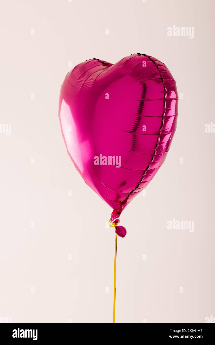 Bulle verticale en forme de coeur rose brillant flottant sur fond blanc avec espace de copie Banque D'Images