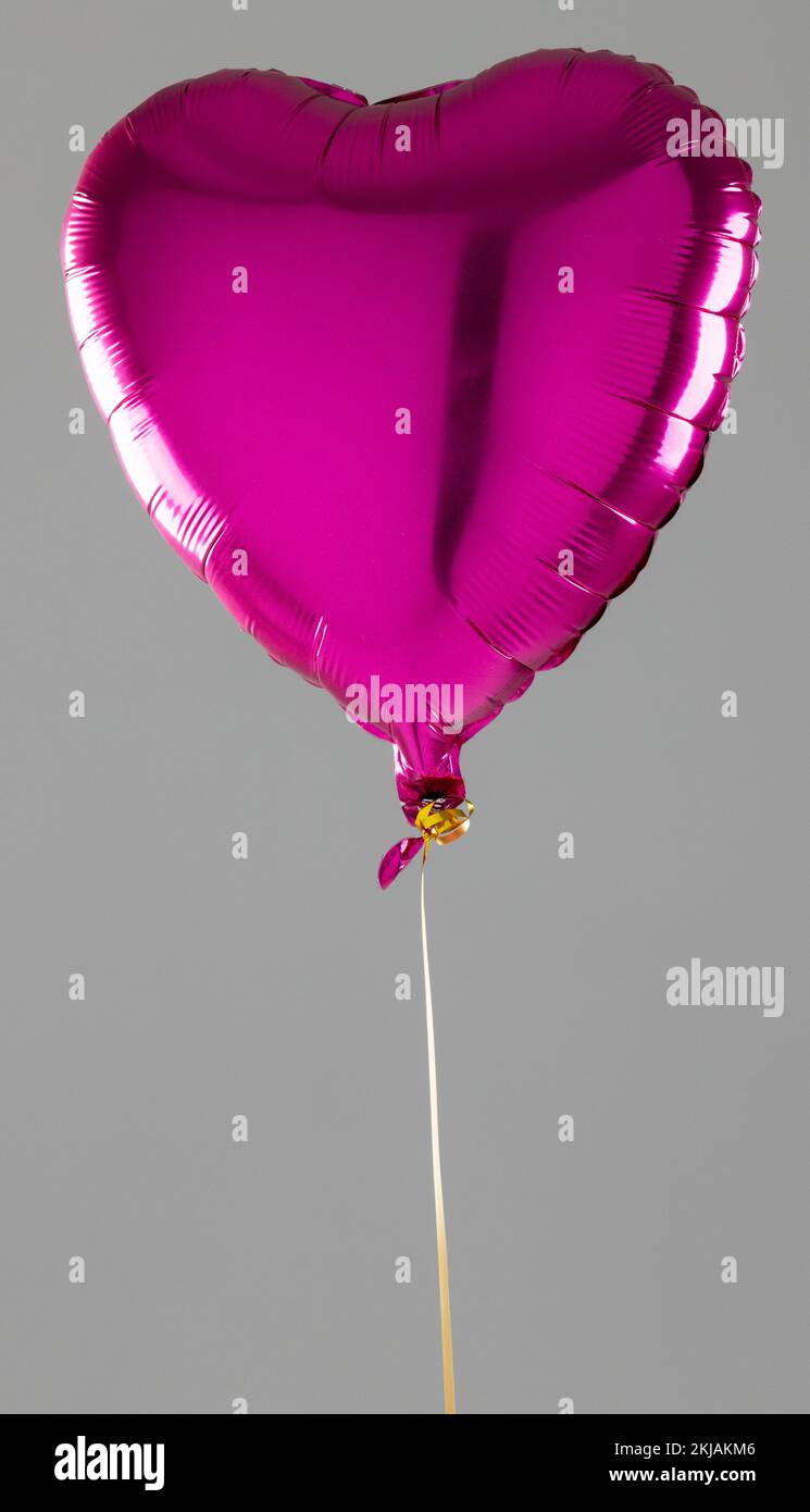 Bulle verticale en forme de coeur rose brillant flottant sur fond gris avec espace de copie Banque D'Images
