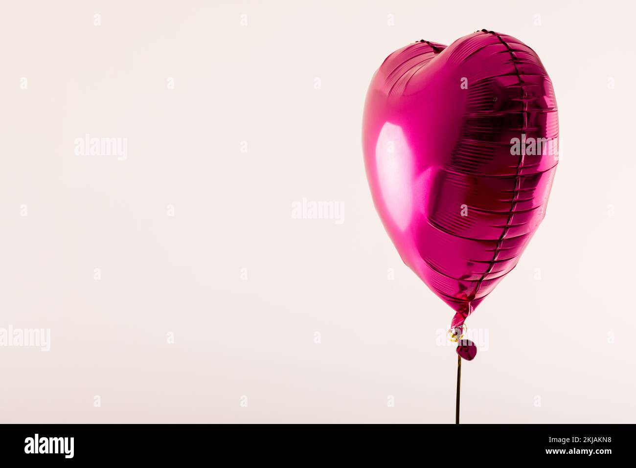 Ballon rose brillant en forme de coeur flottant sur fond blanc avec espace de copie Banque D'Images