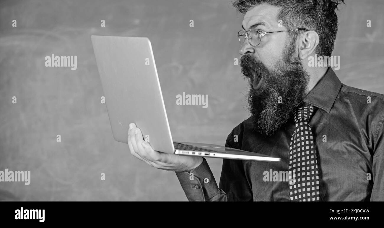 Des informations choquantes. Hipster professeur porter lunettes et cravate tient ordinateur portable surfer sur Internet. Des nouvelles choquantes. Professeur barbu homme choqué avec Banque D'Images