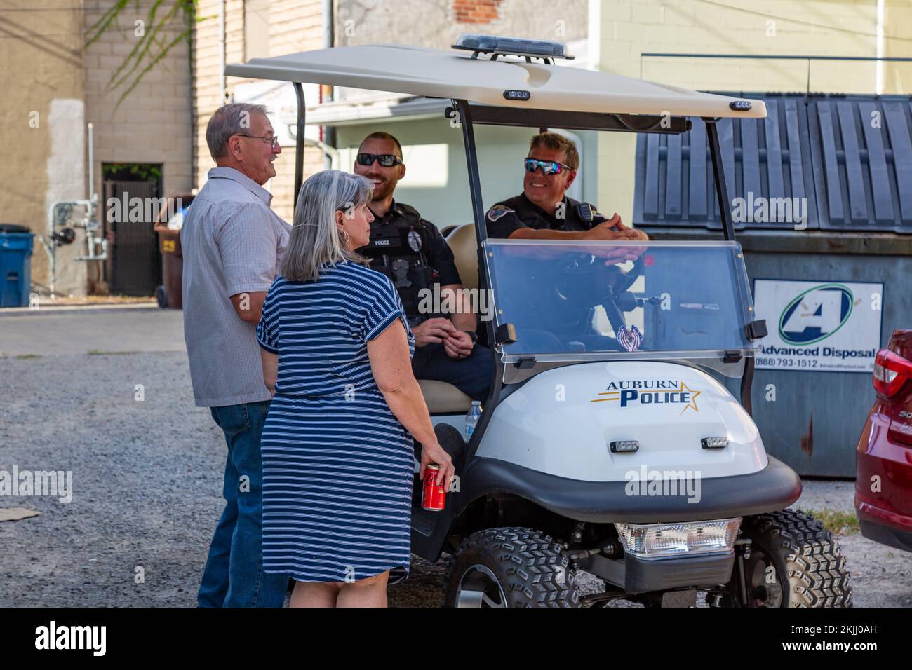 Les officiers du service de police d'Auburn s'assoient dans une voiturette de golf Club car marquée tout en interagissant avec un couple à Auburn, Indiana, États-Unis. Banque D'Images