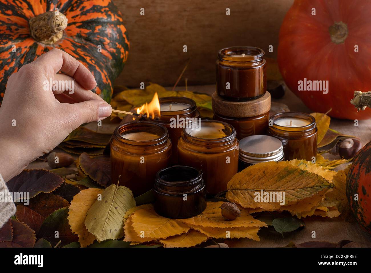 les bougies de soja légères brûlent dans des pots en verre. Feuilles d'arbre, citrouille. Confort à la maison. Bougie dans un pot brun. Parfum et lumière. Bougie parfumée faite à la main. Aromathérapie. Ambiance d'automne. Décoration chaleureuse à l'automne. Banque D'Images