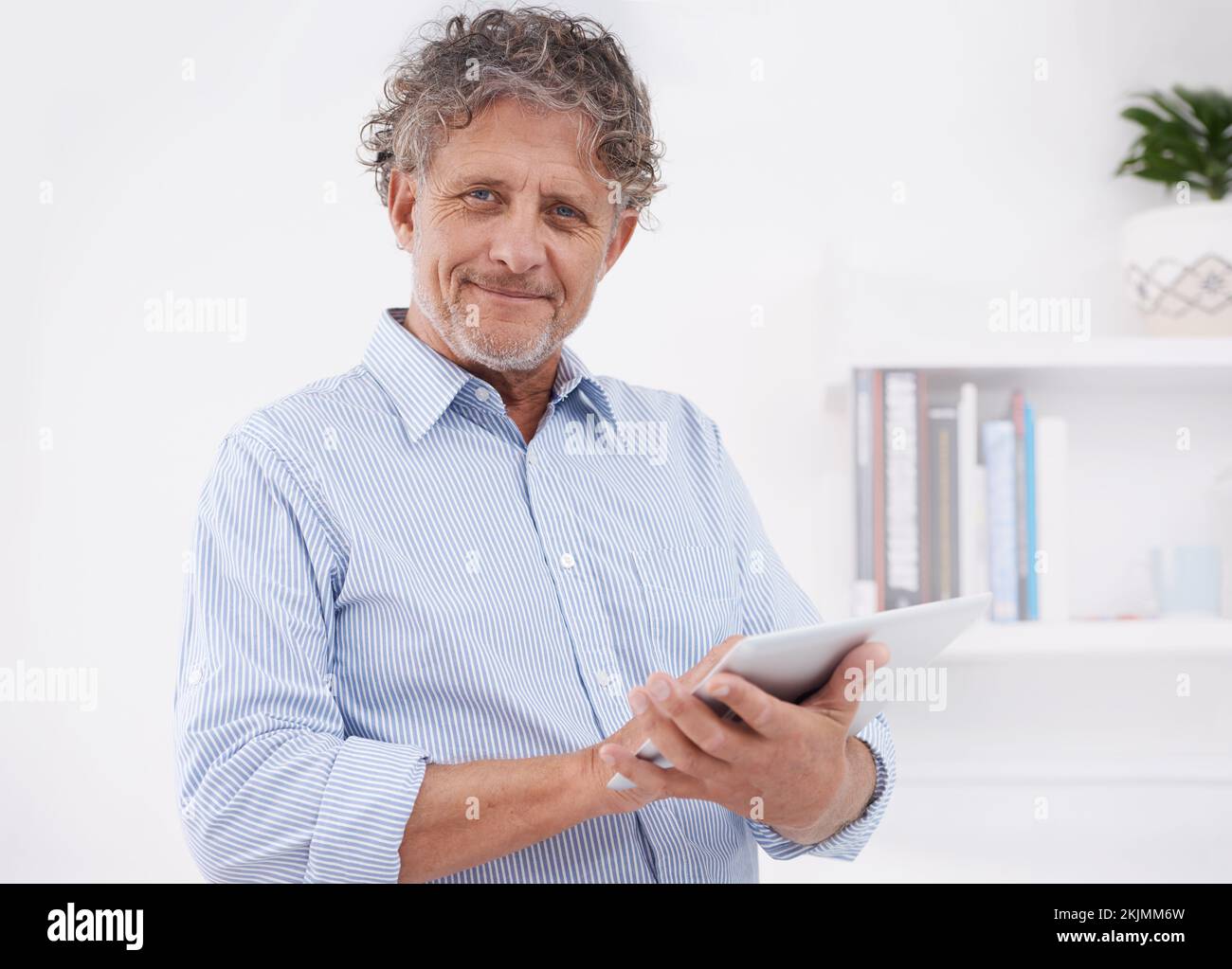 J'en suis bien à l'affiche. Portrait d'un homme d'affaires heureux debout dans son bureau et utilisant une tablette. Banque D'Images