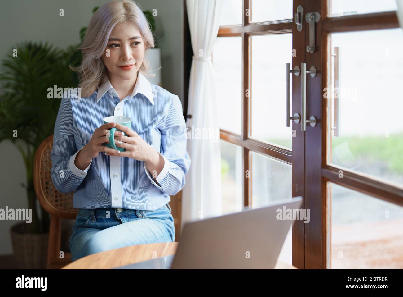 Portrait d'une femme d'affaires asiatique qui boit du café tout en travaillant avec un ordinateur sur son bureau Banque D'Images