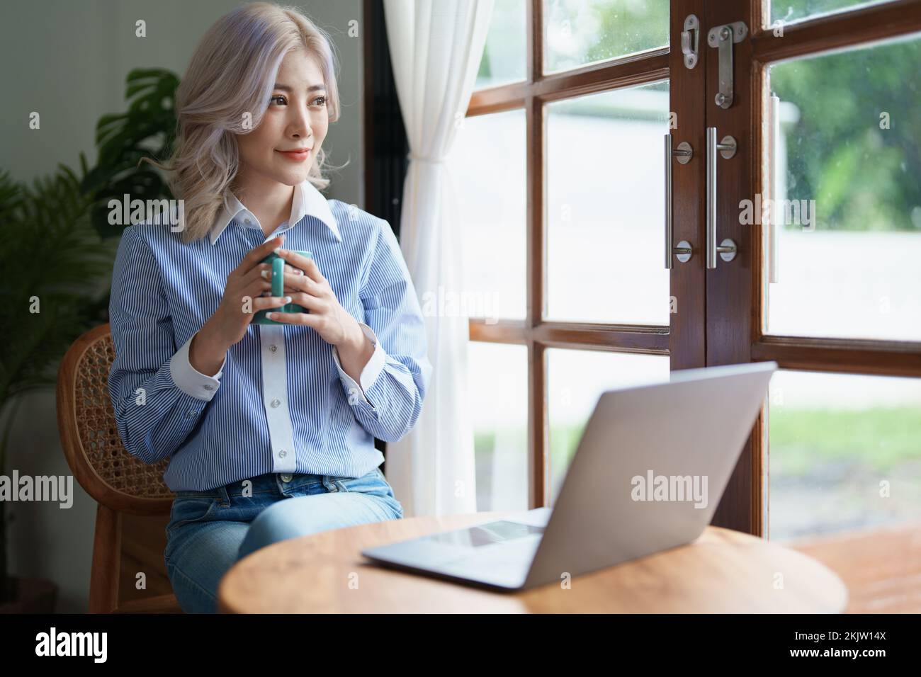 Portrait d'une femme d'affaires asiatique qui boit du café tout en travaillant avec un ordinateur sur son bureau Banque D'Images