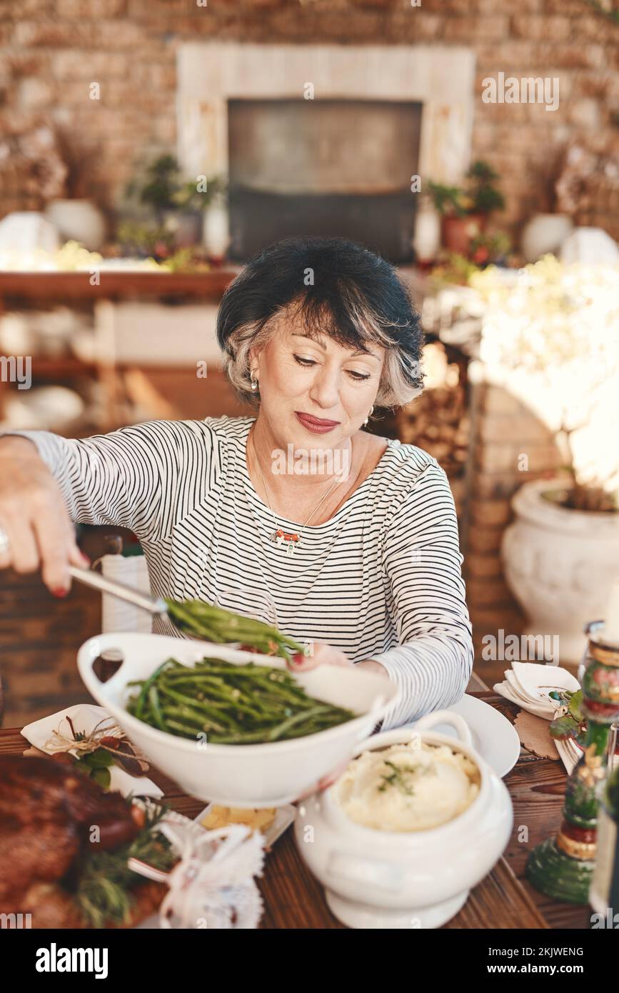 Table de Thanksgiving et femme âgée avec des légumes servant à la fête de la nourriture pour la célébration des États-Unis. Fêtes, fêtes et fêtes de fin d'année à la maison Banque D'Images
