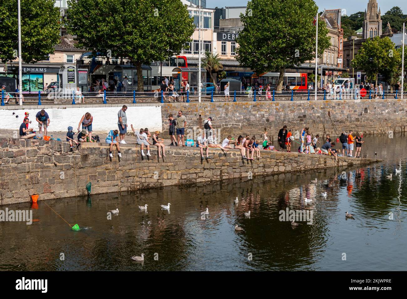 Les vacanciers pêchent des crabes sur la cale du port de Torquay. Banque D'Images