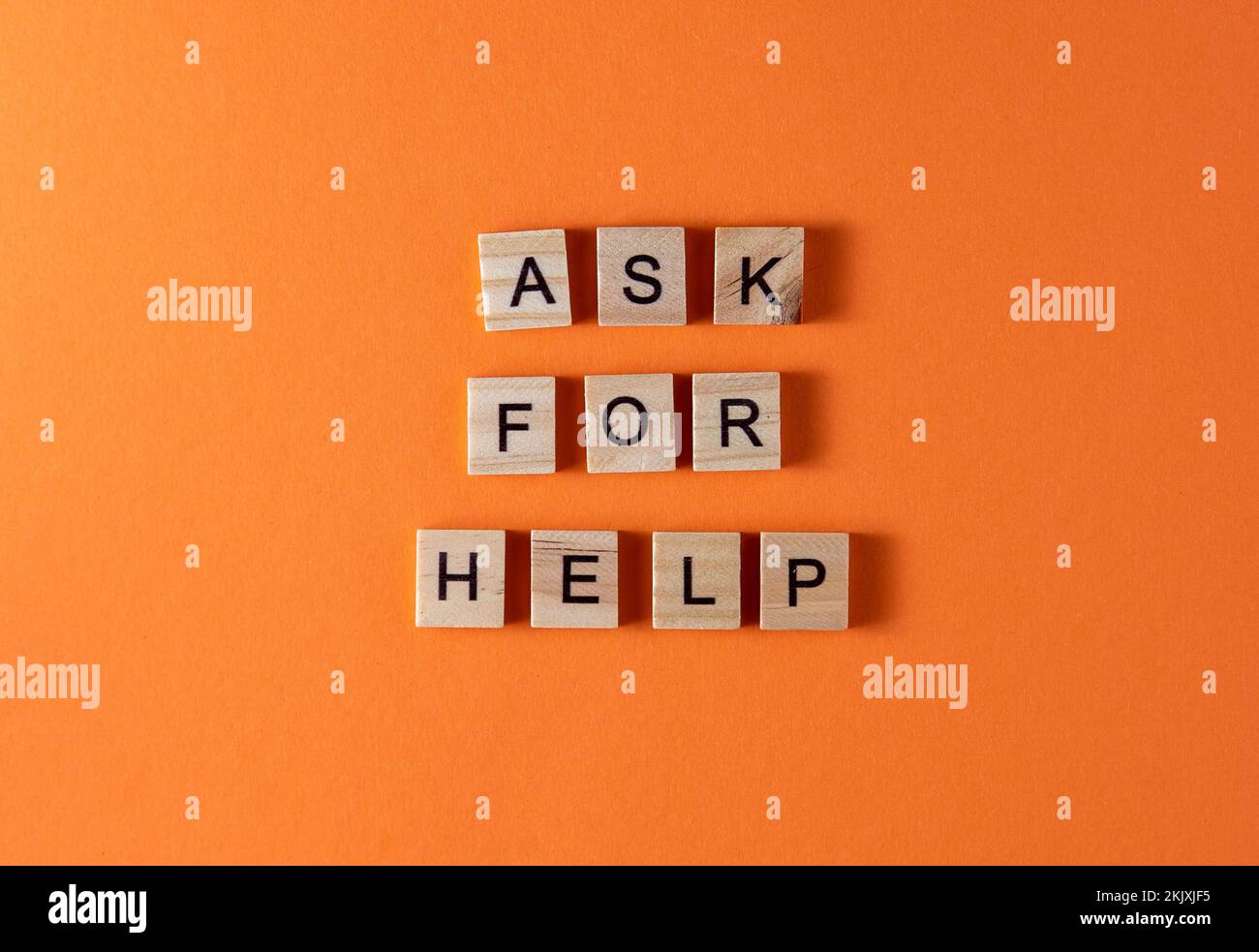 Demandez une phrase de mot d'aide en lettres en bois. Motivation et slogan. Arrière-plan orange. Banque D'Images