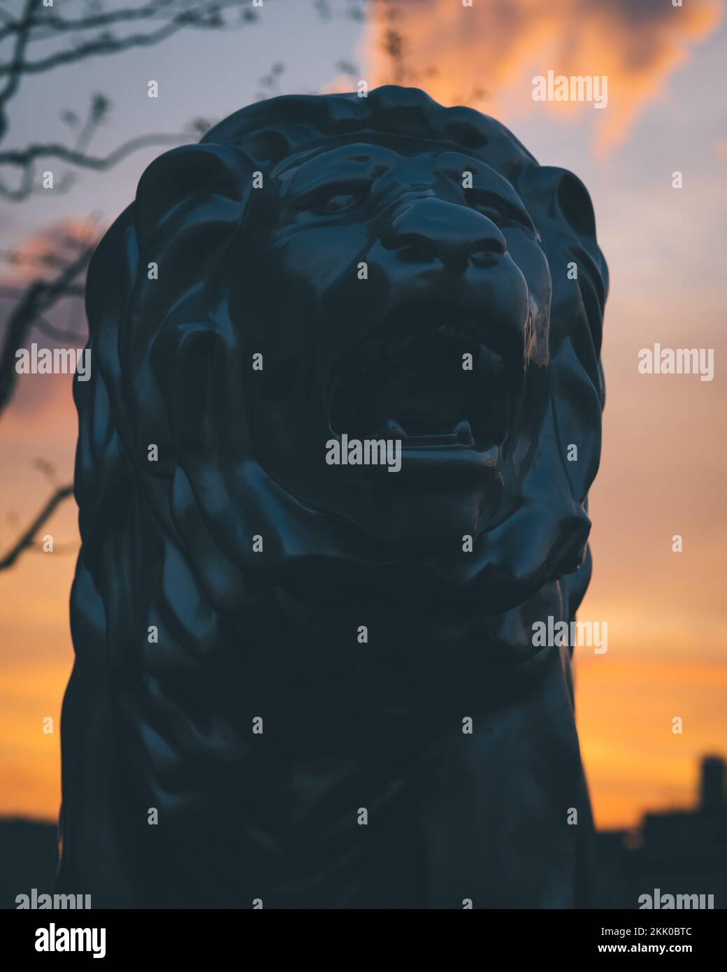 Une statue de lion en pierre noire au coucher du soleil, avec un ciel au coucher du soleil dans le backgound Banque D'Images