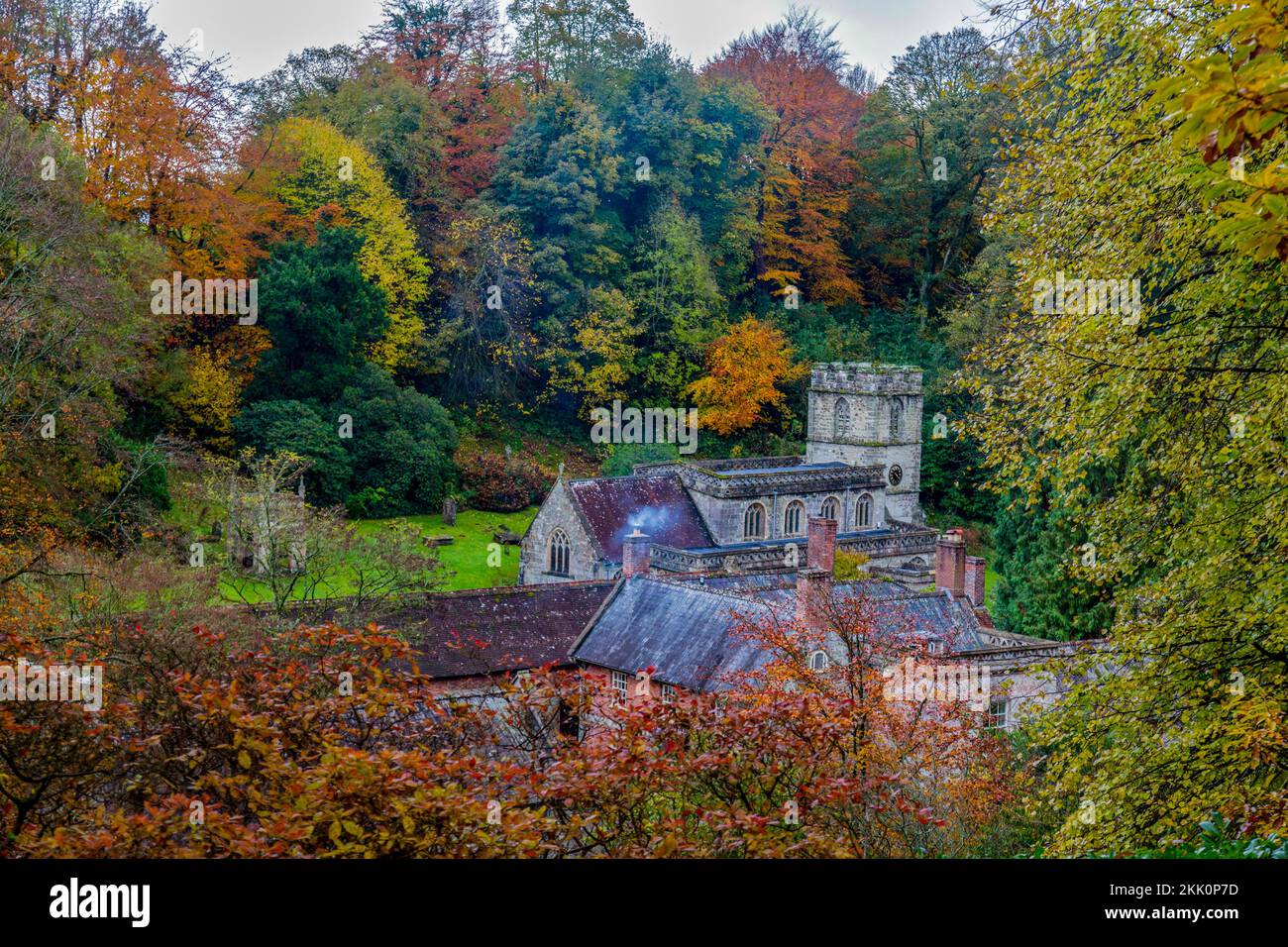 Spectaculaire couleur d'automne sur les arbres boisés, une cheminée à fumer et l'église paroissiale de Stourhead Gardens, Wiltshire, Angleterre, Royaume-Uni Banque D'Images