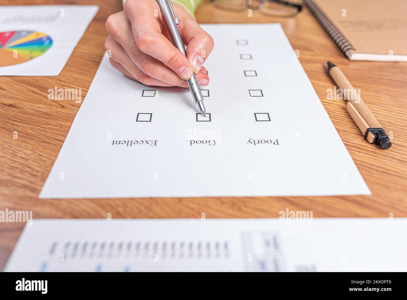 La main d'une femme remplit une liste de contrôle ou un test d'examen donnant une note de bon ou de mauvais. Banque D'Images