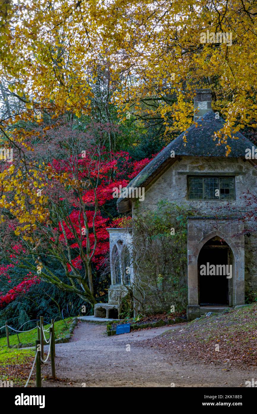 La spectaculaire couleur automnale entoure le cottage gothique de chaume à Stourhead Gardens, Wiltshire, Angleterre, Royaume-Uni Banque D'Images