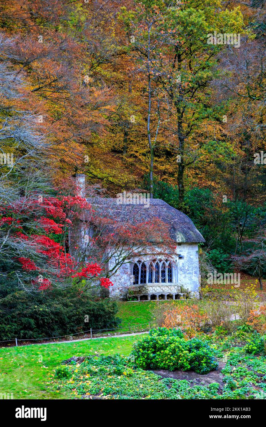 La spectaculaire couleur automnale entoure le cottage gothique de chaume à Stourhead Gardens, Wiltshire, Angleterre, Royaume-Uni Banque D'Images