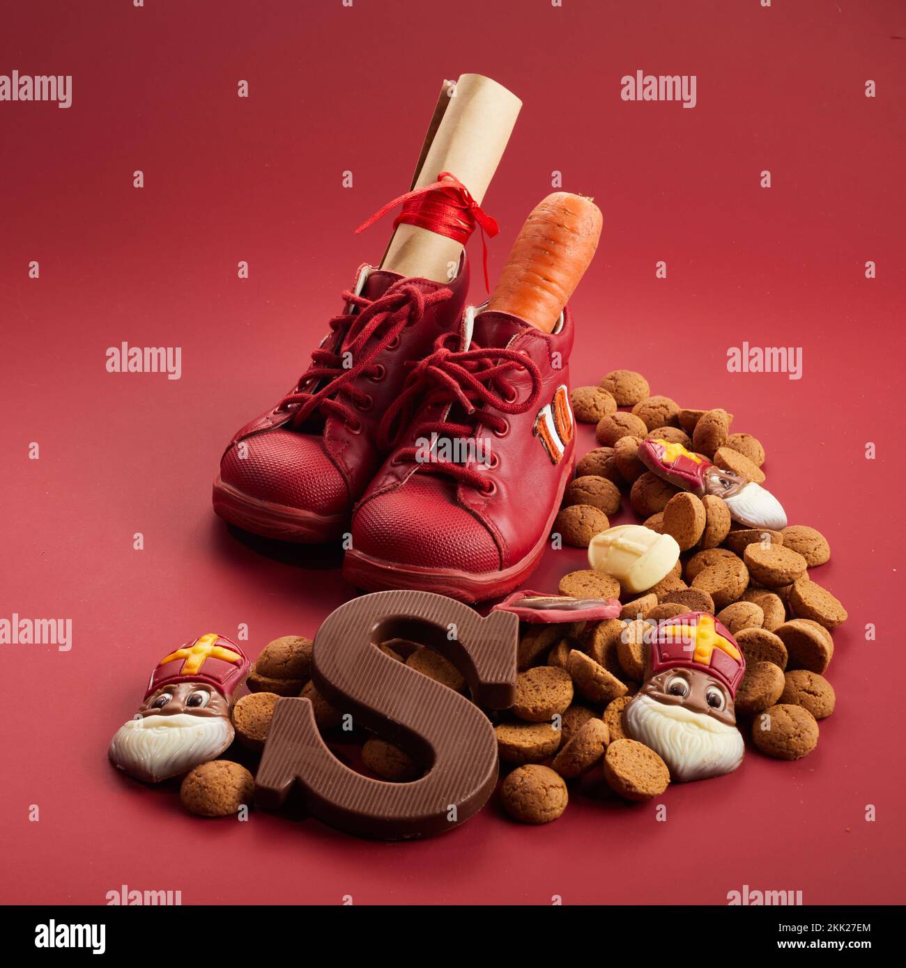 Saint Nicholas - jour de Sinterklaas avec la chaussure, la carotte et les bonbons traditionnels sur fond rouge Banque D'Images