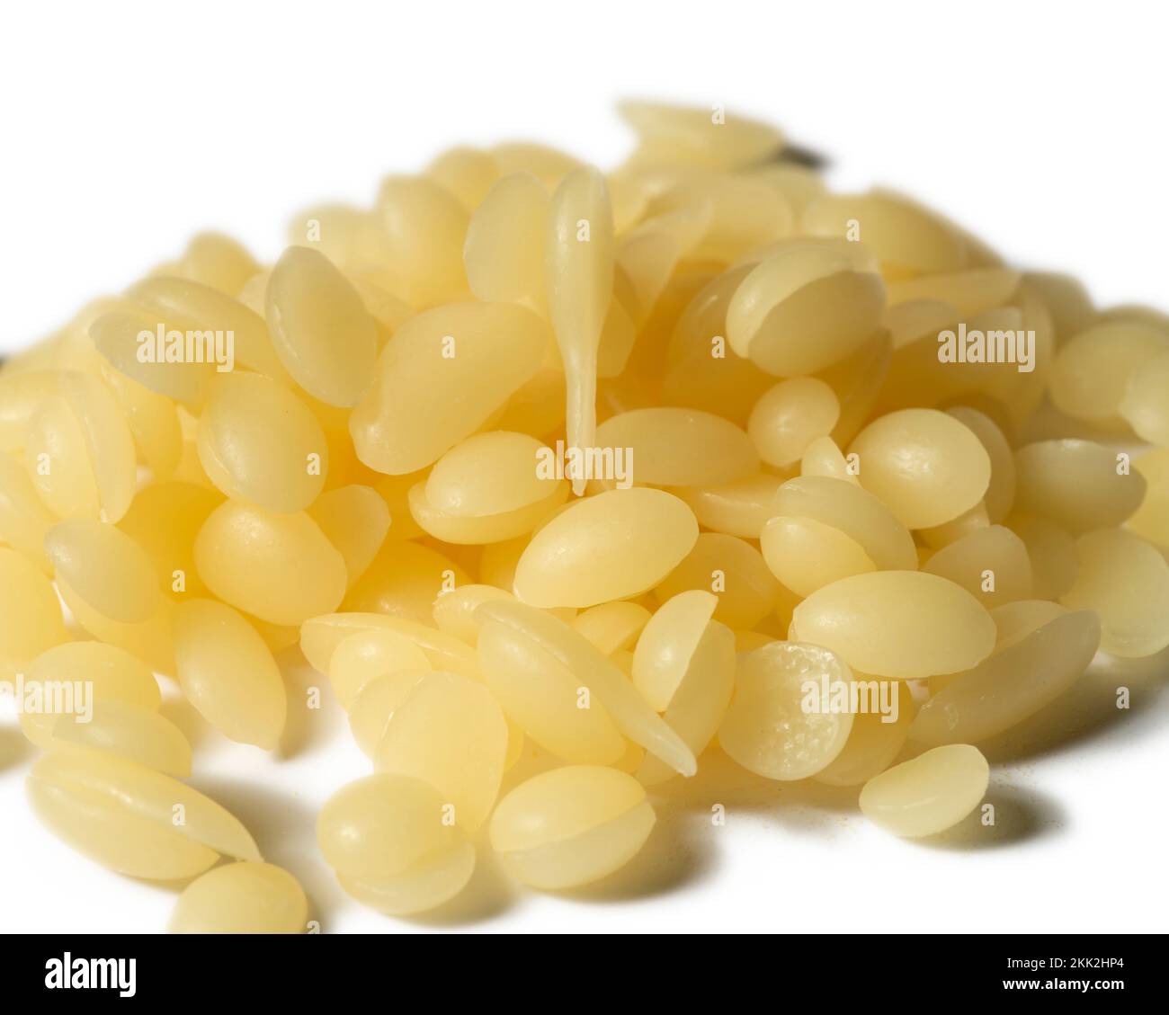 Pile de perles de cire d'abeille jaune naturelle isolées sur un fond blanc Banque D'Images