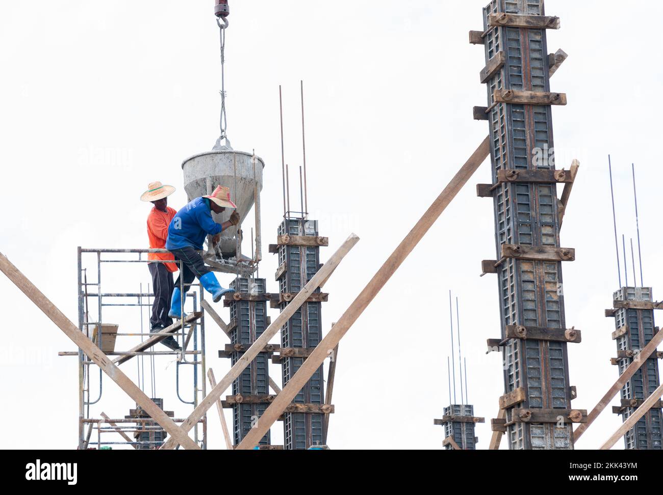 Un travailleur utilise une grue pour soulever le mortier pour déposer les colonnes structurelles sur le chantier de construction. Banque D'Images