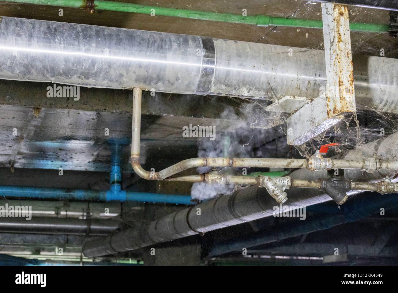 Fuite de vapeur à travers une fissure dans le chauffage du tuyau  d'échappement sous l'usine au sol Photo Stock - Alamy