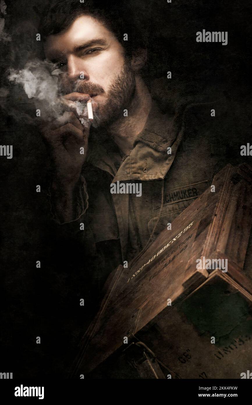 Soldat d'infanterie de terre de la Seconde Guerre mondiale à l'air déterminé tout en fusant sur UN Cigarette et transport D'UNE boîte remplie de munitions à armes légères Pendant la bataille de Banque D'Images