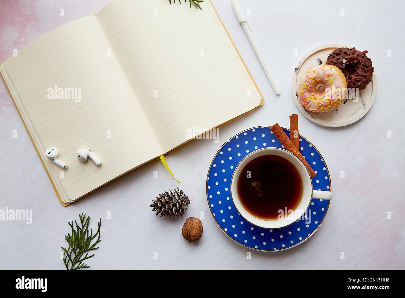 Maquette de bloc-notes vide avec écouteurs sans fil, tasse à café avec beignets. Travail en ligne, freelance, participation à un séminaire en ligne, écoute de musique ou de livres audio, nouvelle norme. Maison confortable. Banque D'Images