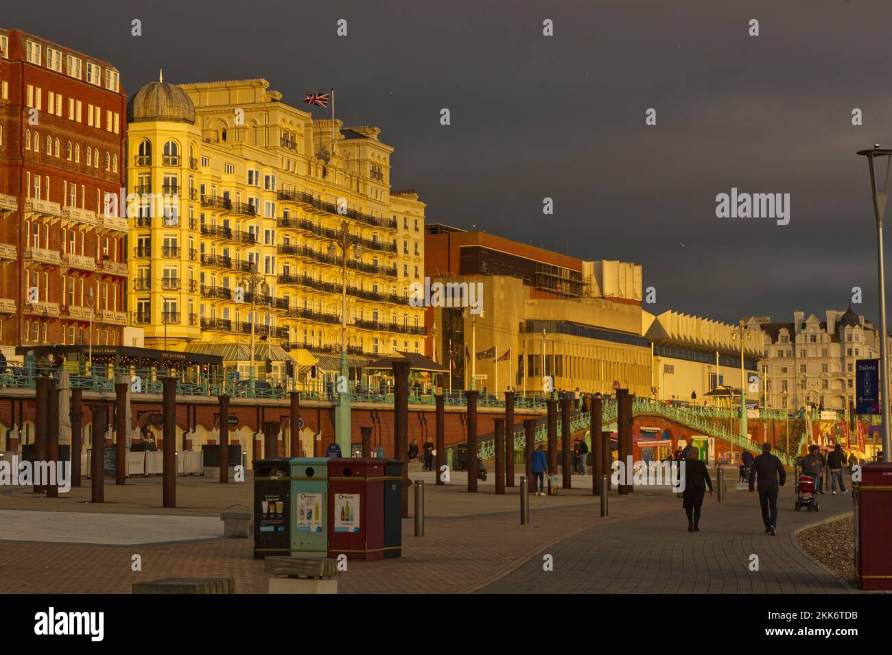 Promenade en bord de mer avec le Grand Hotel dans une lumière spectaculaire de coucher de soleil avec ciel sombre et moody. East Sussex, Angleterre. Avec les gens qui marchent. Banque D'Images
