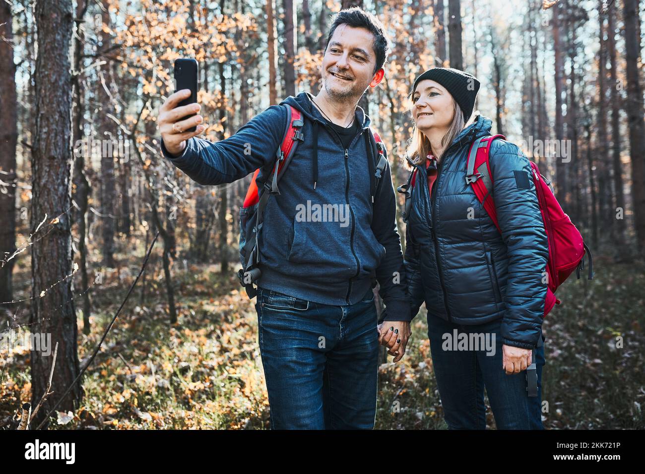 Couple prenant une photo de selfie pendant un voyage de vacances. Randonneurs avec sacs à dos marchant sur le chemin en forêt par beau temps. Loisirs actifs à proximité de la nature Banque D'Images