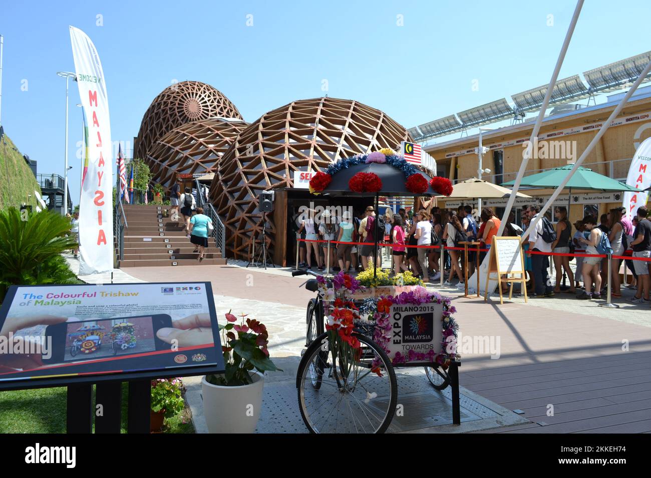 Entrée au pavillon de Malaisie à l'EXPO Milano 2015 avec un pousse-pousse décoré de fleurs en papier pour les instantanés et une file de touristes qui attendent. Banque D'Images