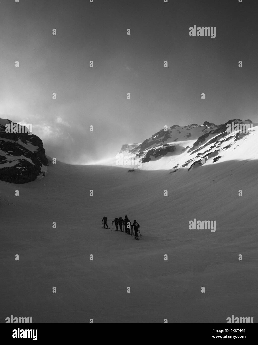 La photo verticale en niveaux de gris d'un groupe de personnes qui skaient sur les montagnes enneigées d'Entremont Banque D'Images