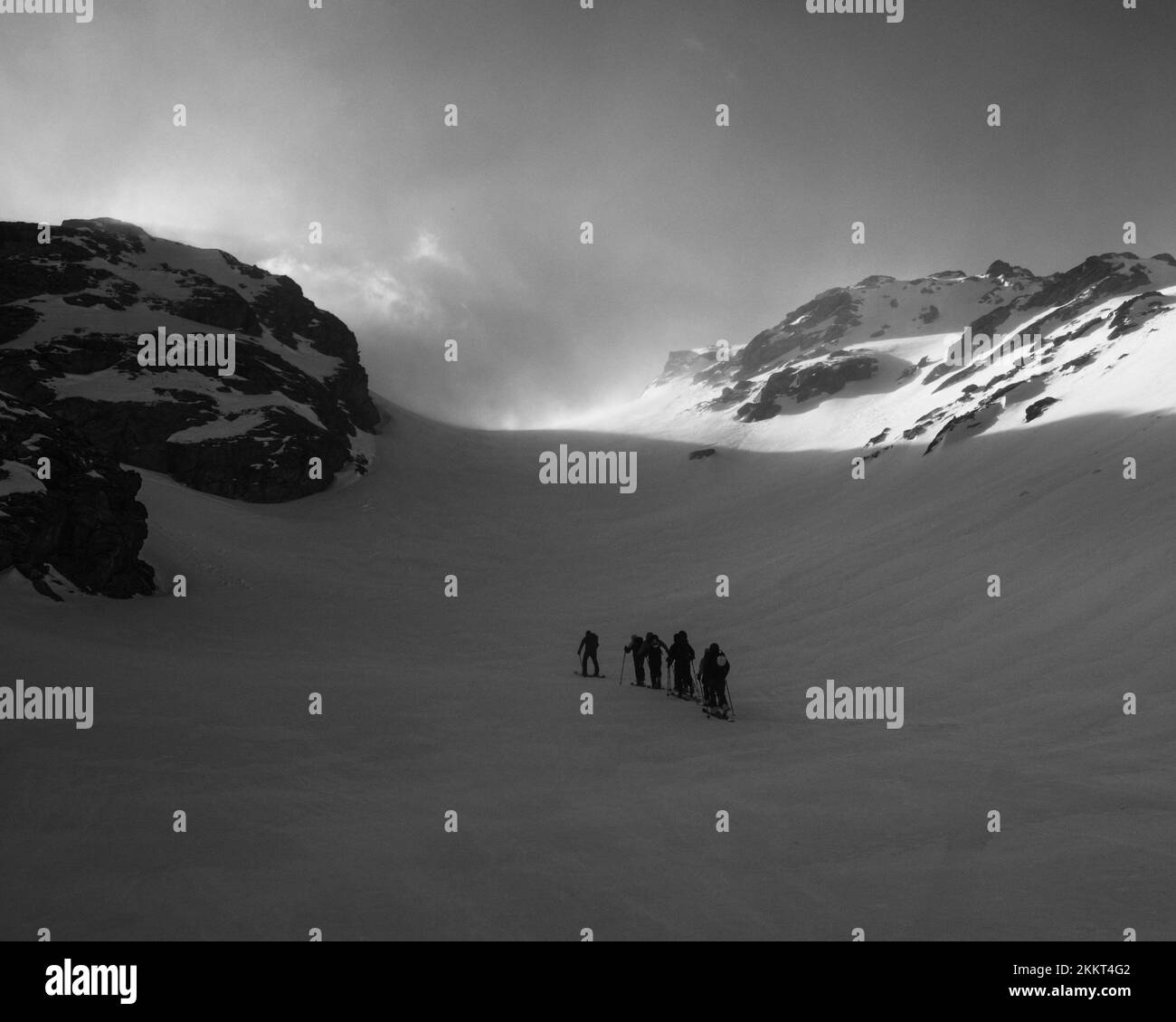 La photo en niveaux de gris d'un groupe de personnes skant sur les montagnes enneigées d'Entremont Banque D'Images