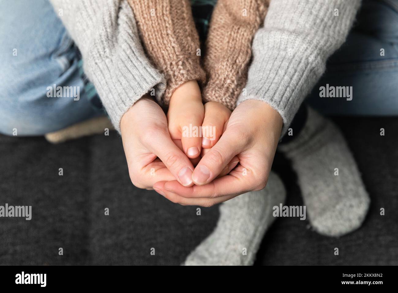 Femmes tenant la main de fils, pull tricoté et chaussettes en arrière-plan. Accueil chaleureux et concept de famille. Banque D'Images