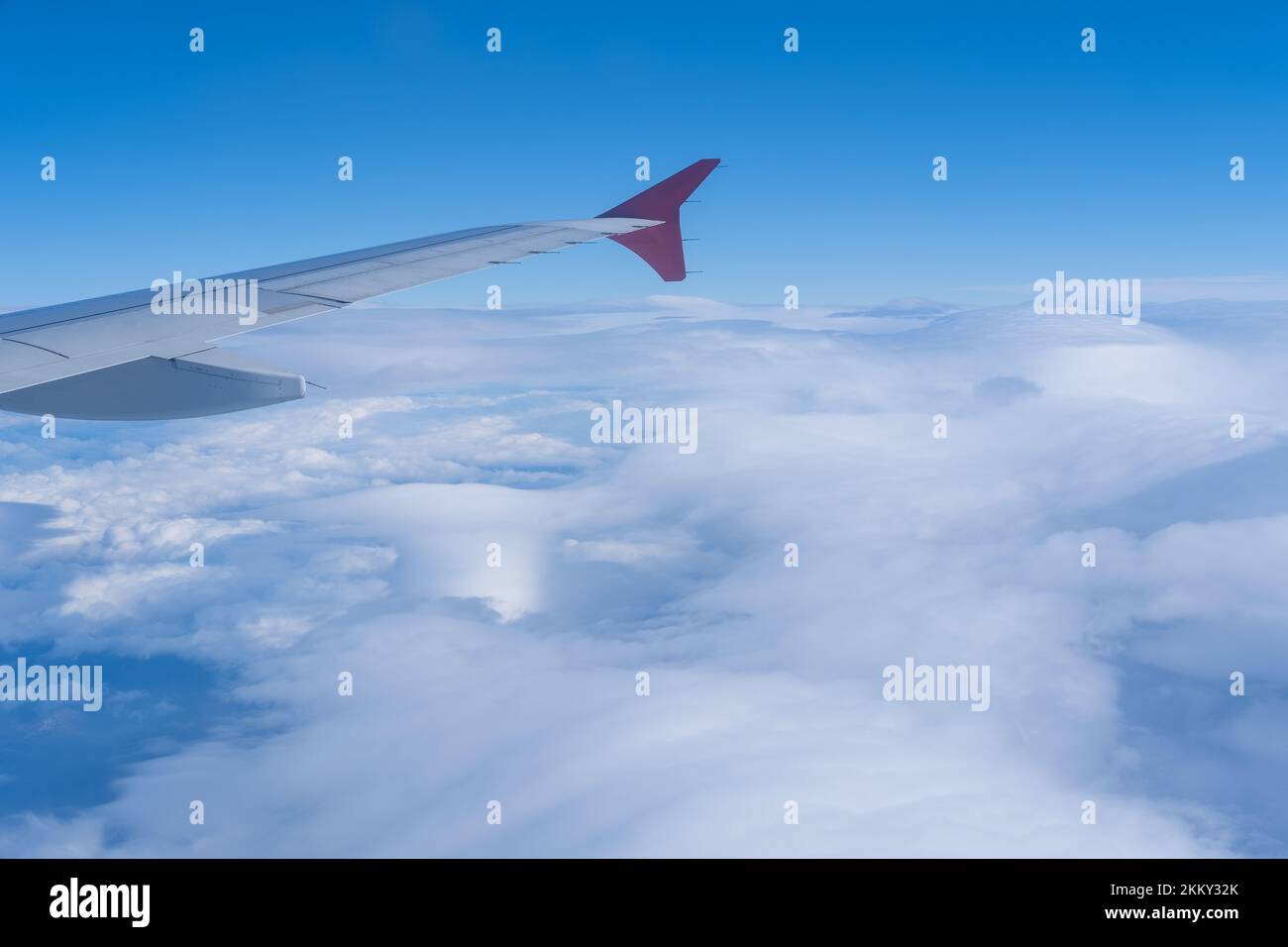 La vue de la fenêtre de l'avion sur l'aile de l'avion contre le fond des nuages moelleux et du ciel bleu. Le concept de voyage. Banque D'Images
