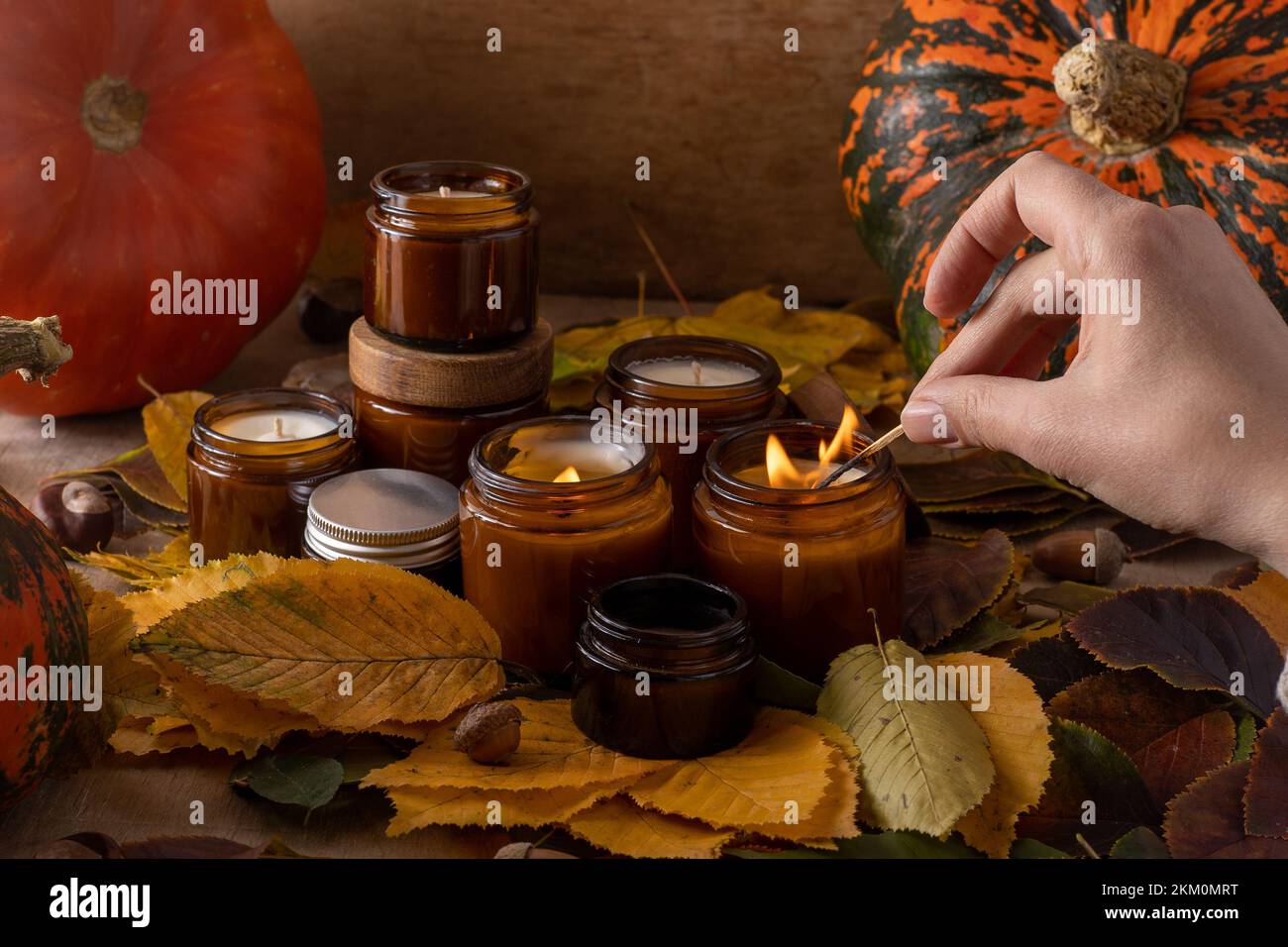 les bougies de soja légères brûlent dans des pots en verre. Feuilles d'arbre, citrouille. Confort à la maison. Bougie dans un pot brun. Parfum et lumière. Bougie parfumée faite à la main. Aromathérapie. Ambiance d'automne. Décoration chaleureuse à l'automne. Banque D'Images