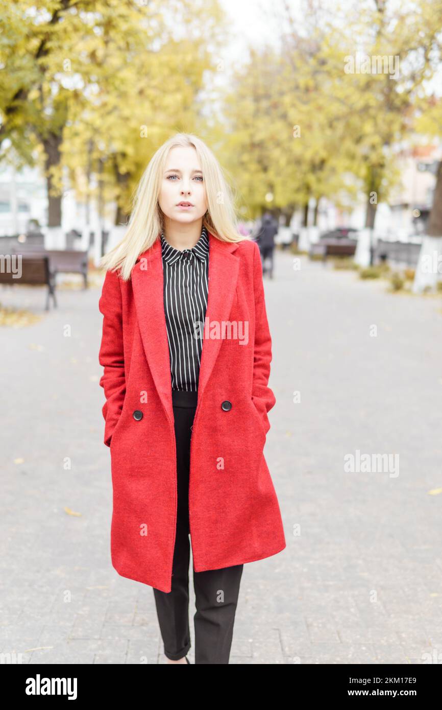 Une jeune femme blonde se promène dans la ville d'automne sous un manteau  rouge. Le concept de style urbain et de style de vie Photo Stock - Alamy