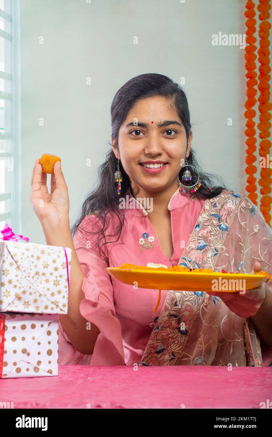 Portrait d'une sœur joyeuse tenant une assiette de ladoos à l'occasion de Raksha Bandhan Banque D'Images