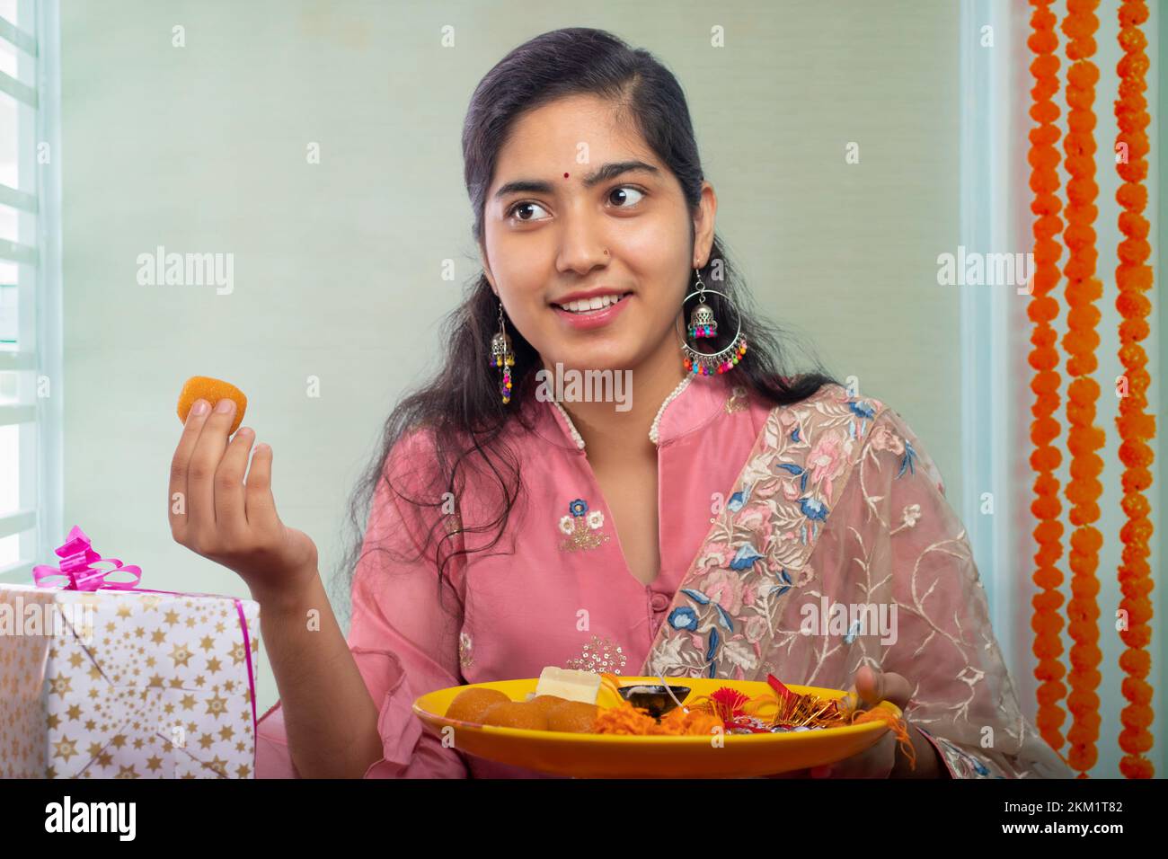 Portrait d'une sœur joyeuse tenant une assiette de ladoos à l'occasion de Raksha Bandhan Banque D'Images