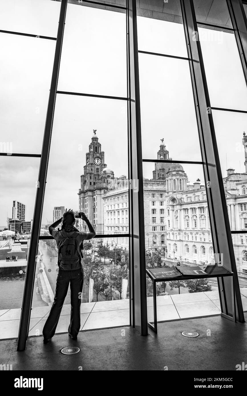 Une échelle de gris d'un homme surplombant le bâtiment Liver Bird du musée de Liverpool, un cliché vertical Banque D'Images