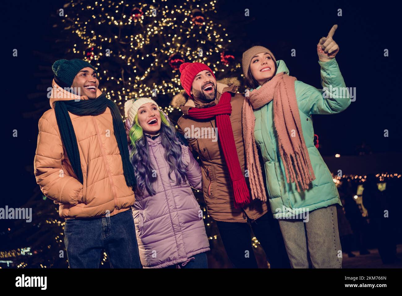 Photo de curieux excités quatre copains portent des coupe-vent regardant des activités de Noël ensemble à l'extérieur du parc urbain du marché Banque D'Images