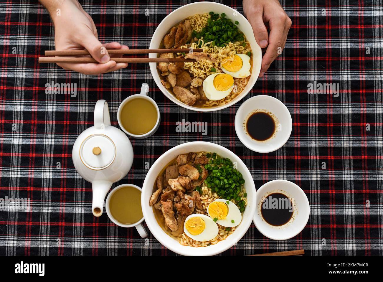 Morceau de poulet en baguettes avec des mains de ramen japonais et de mâles Banque D'Images