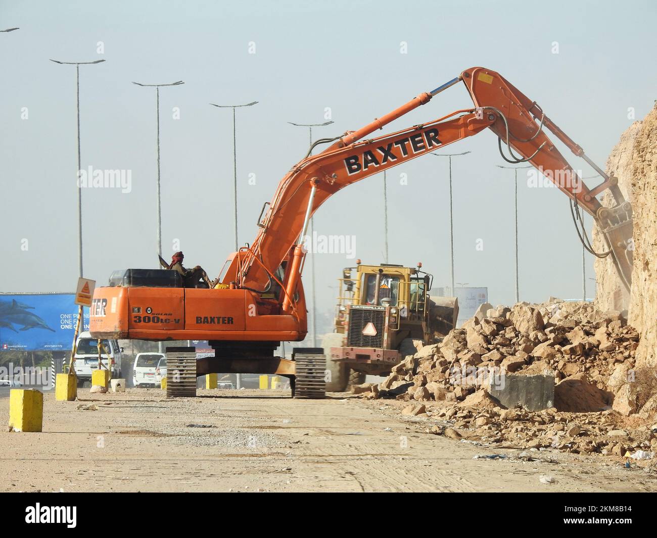 Le Caire, l'Egypte, 26 novembre 2022: Excavatrice hydraulique de démolition sur chenilles enlever les prats d'une colline ou d'une montagne sur le bord de la route pour développer et élargir t Banque D'Images