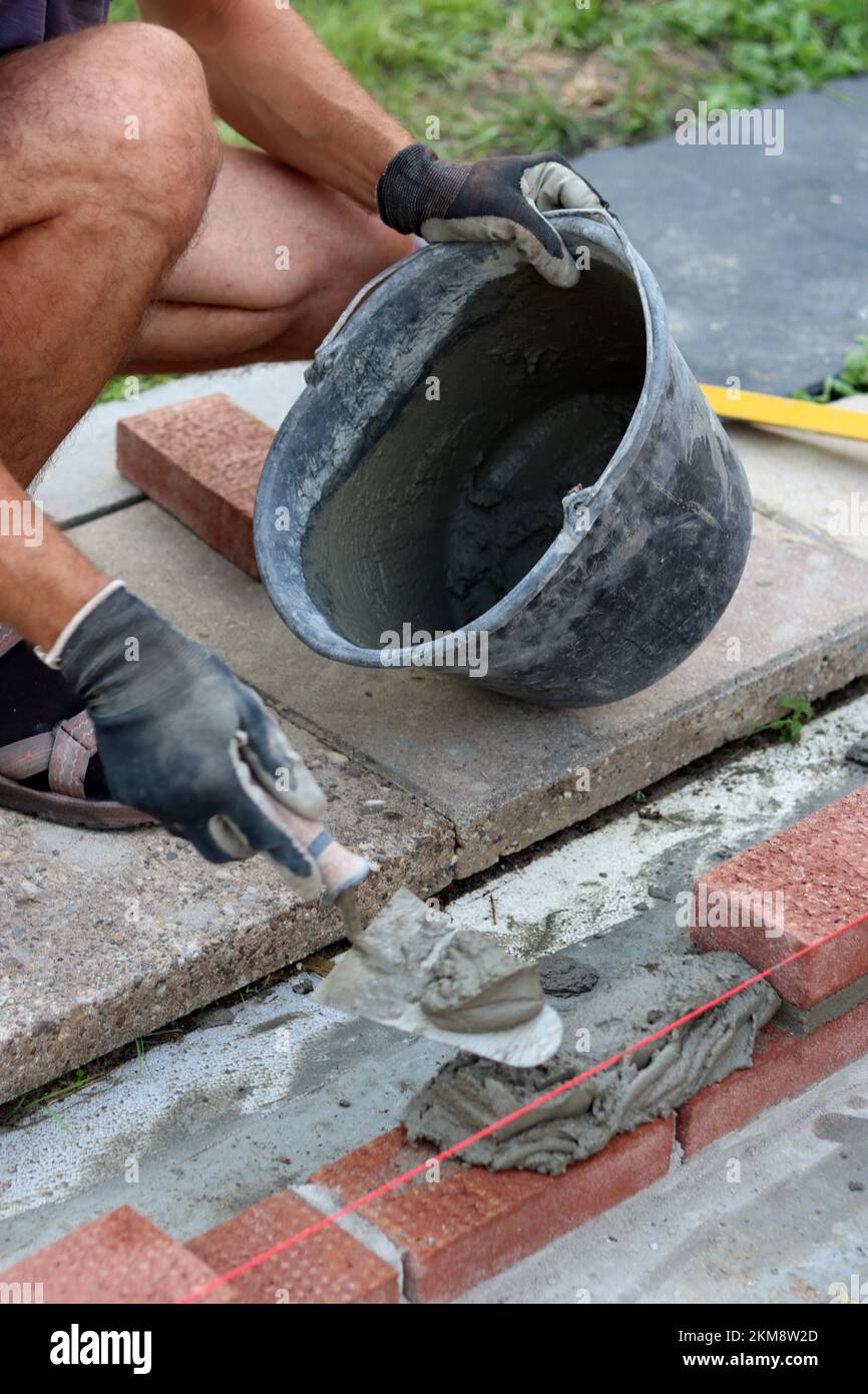 Travaux de construction en cours. Homme constructeur travaillant avec des briques rouges. Photo de près du mur de maçonnerie. Banque D'Images