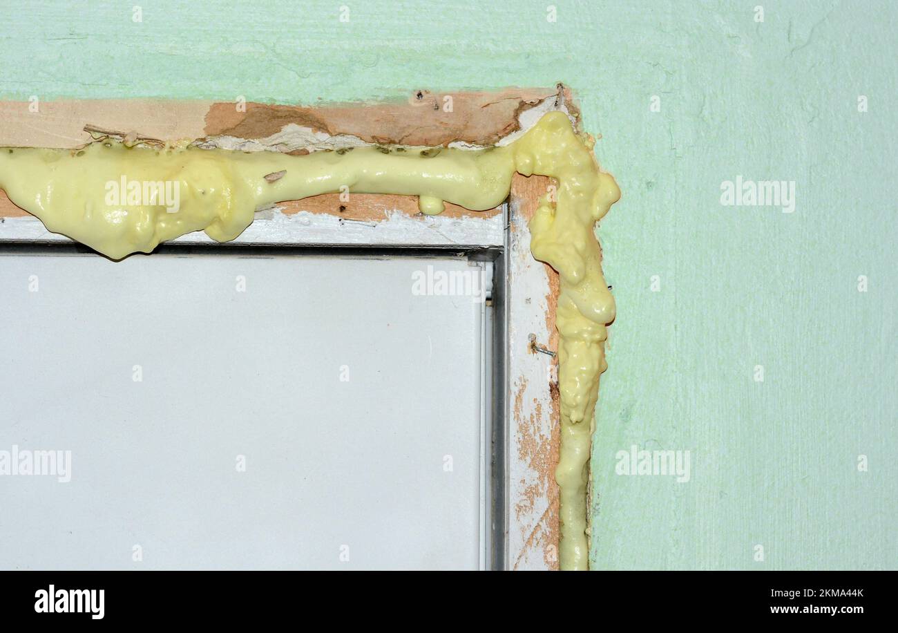 L'isolant en mousse est pulvérisé dans les fissures autour d'une porte extérieure avant que l'excédent ne soit coupé. Un travail facile pour les propriétaires. Banque D'Images