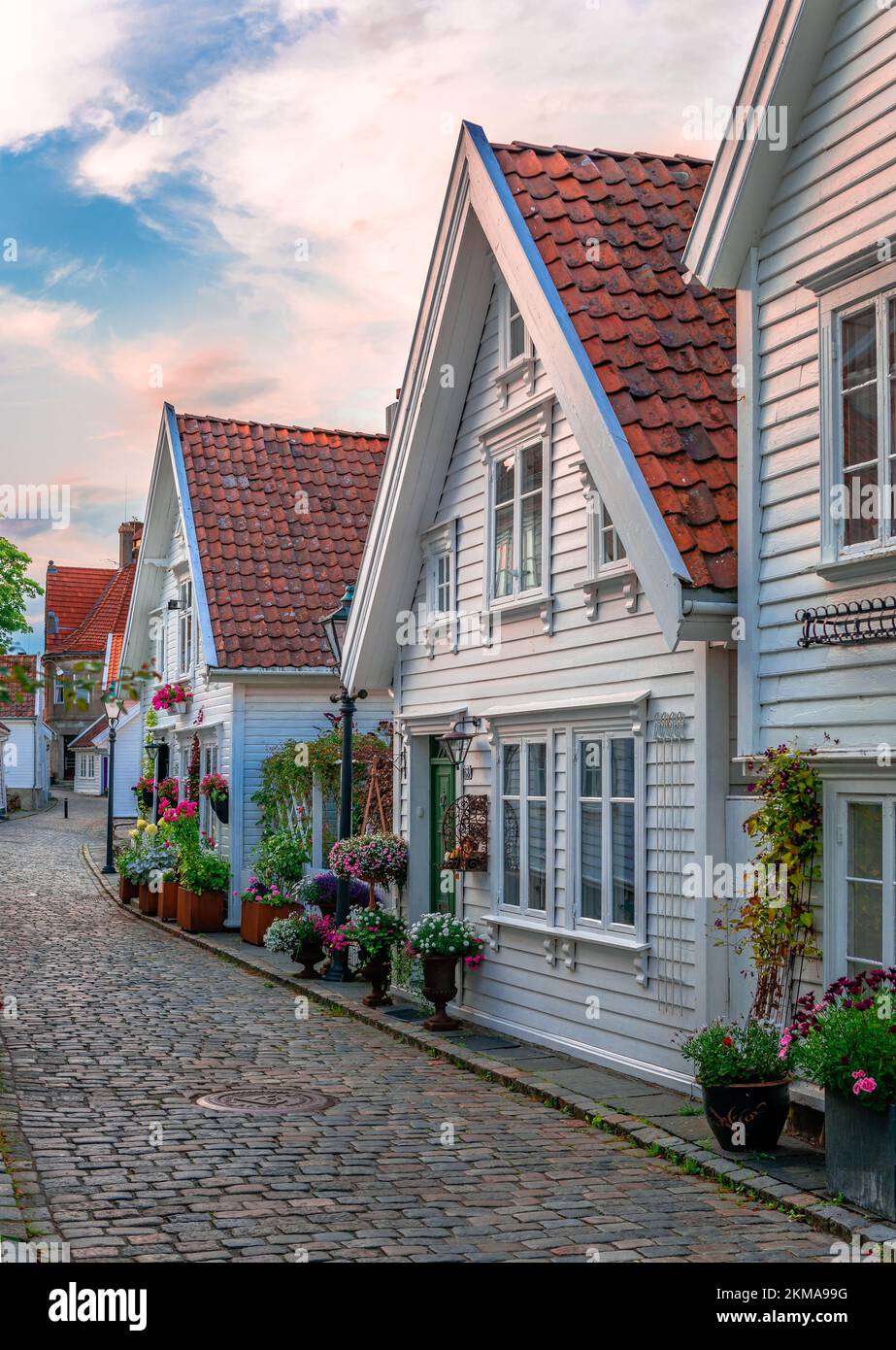 Vue sur Øvre Strandgate, dans la vieille ville de Stavanger, Norvège. Maisons en bois blanc décorées de belles fleurs dans des rues pavées rustiques. Banque D'Images
