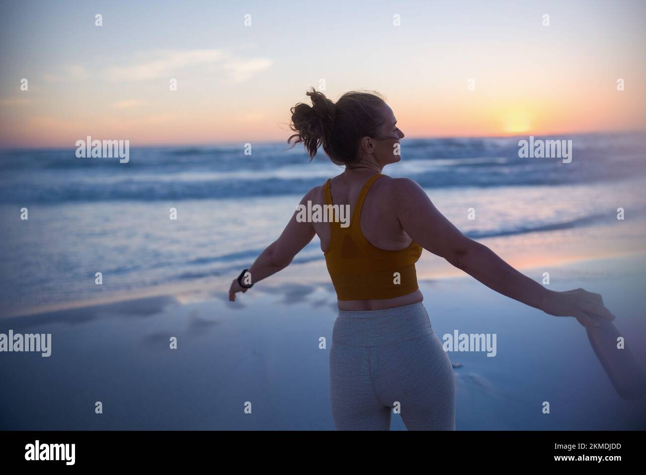 Vue de derrière la femme de forme physique Jogger dans les vêtements de forme physique avec une bouteille d'eau se réjouir. Banque D'Images