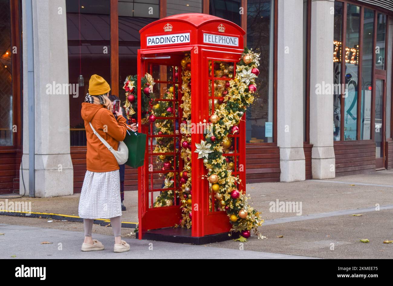 Londres, Angleterre, Royaume-Uni. 26th novembre 2022. Une femme prend une photo d'une boîte téléphonique rouge décorée d'ornements de Noël à Paddington. (Image de crédit : © Vuk Valcic/ZUMA Press Wire) Banque D'Images
