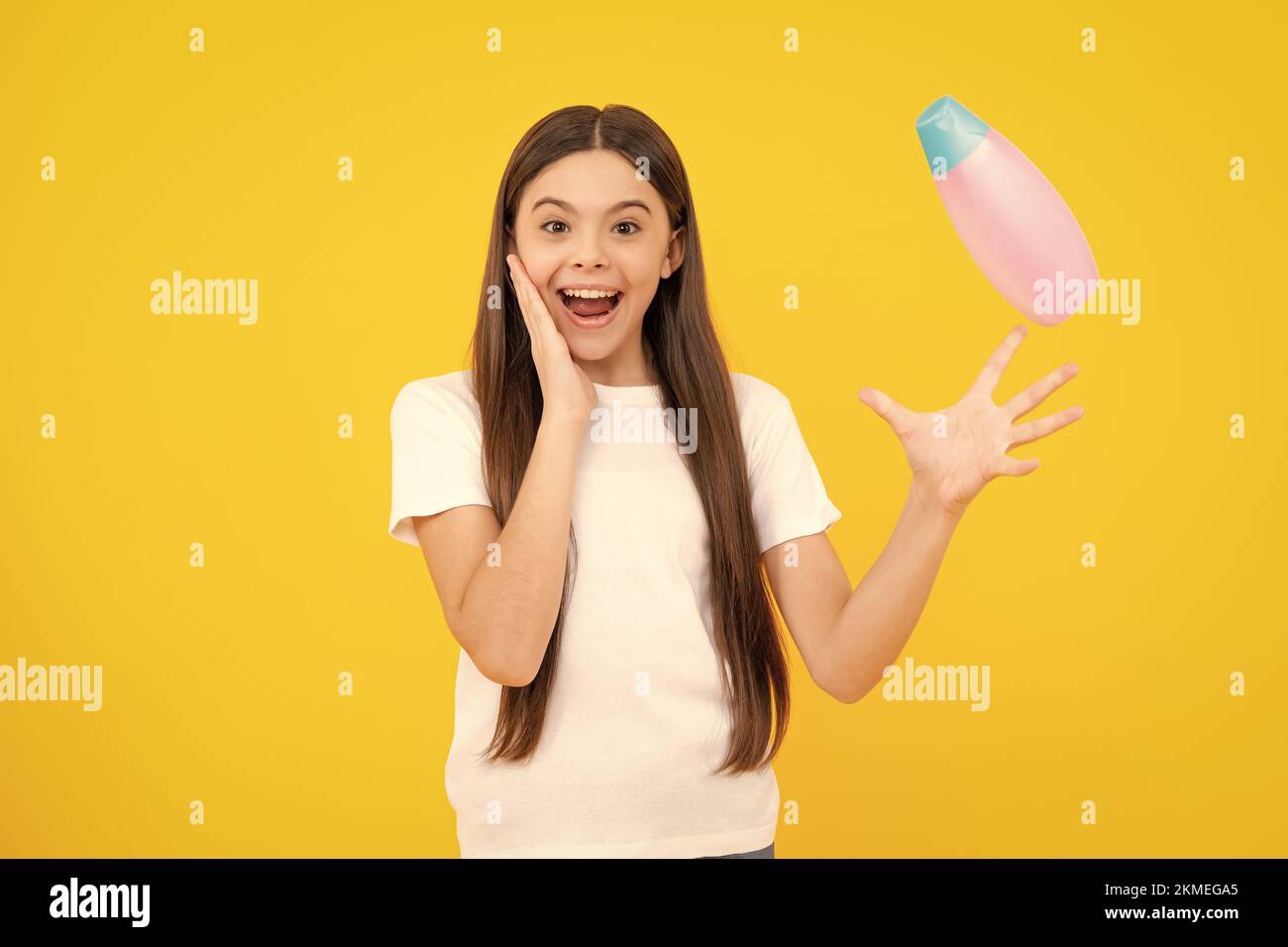 Portrait heureux de l'enfant avec après-shampooing. Soins cosmétiques quotidiens. L'adolescent de 12, 13, 14 ans tient une bouteille de soins pour les cheveux et la peau. Beauté Banque D'Images