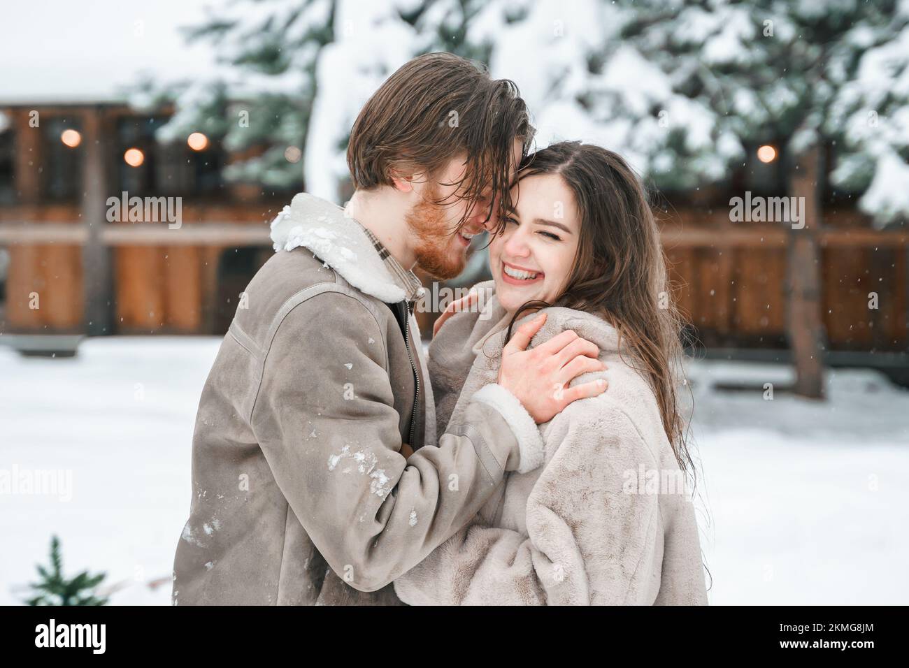 Jeune fille de couple marchant près de la grange avec des patins. Hiver enneigé et froid à la campagne. Patinage, embrasser, s'amuser, rire dans des vêtements élégants, la fourrure Banque D'Images