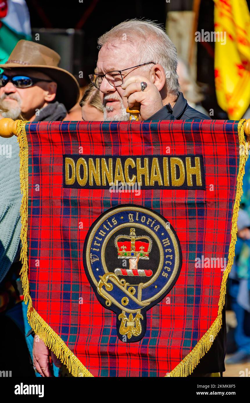 Un homme tient un tartan représentant le clan Donnachaidh lors de la parade des tartans du clan aux Jeux écossais des Highlands à Gulfport, Mississippi. Banque D'Images