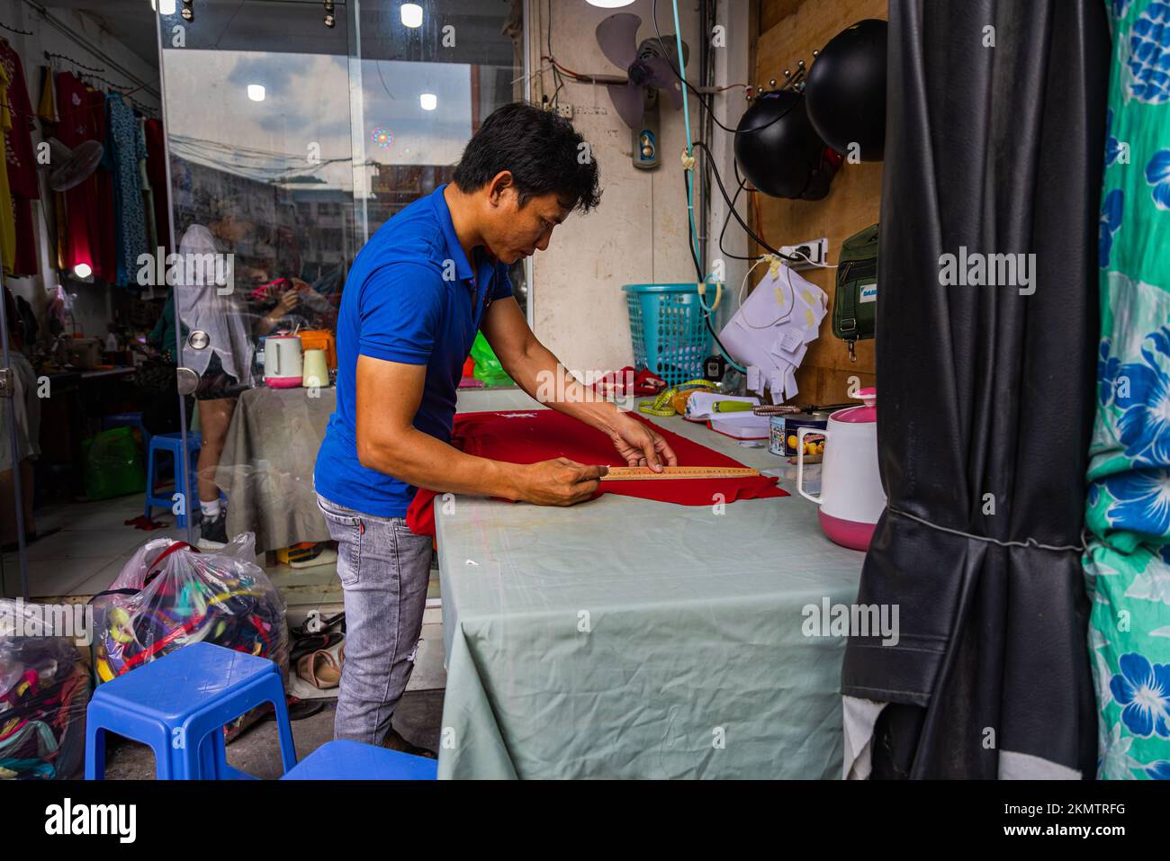 Ho Chi Minh ville, Vietnam - 8 novembre 2022: Dans un petit tailleur à Saigon. Un homme marque le tissu pour faire une robe traditionnelle ao dai, la traditio Banque D'Images