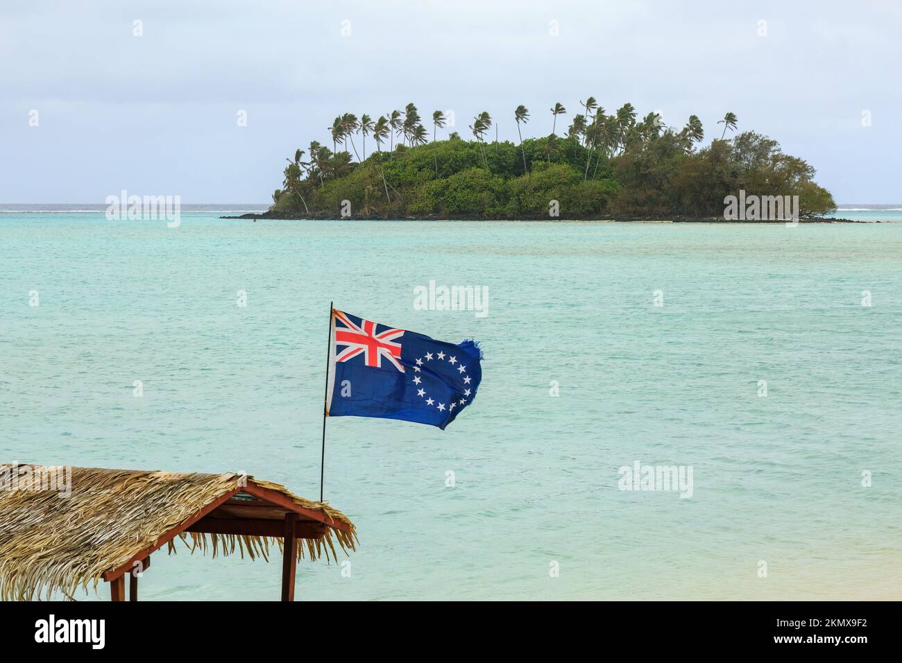 Le drapeau des îles Cook vole depuis l'arrière d'un bateau dans le lagon de Muri, à Rarotonga. En arrière-plan se trouve la minuscule île de Taakoka Banque D'Images