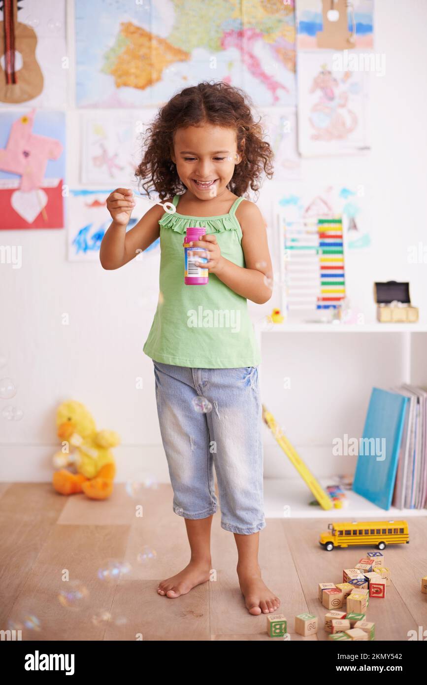 Les bulles sont tellement amusantes. une adorable petite fille soufflant des bulles dans sa chambre. Banque D'Images