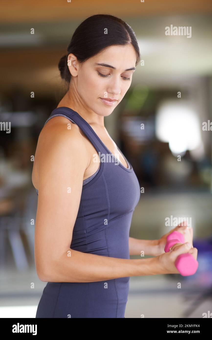 Elle travaille sur ses bras. une jeune femme qui fait de l'exercice avec des poids. Banque D'Images